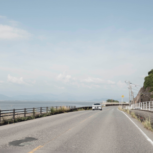 海沿いの道路。白い車が向かいから来ている。